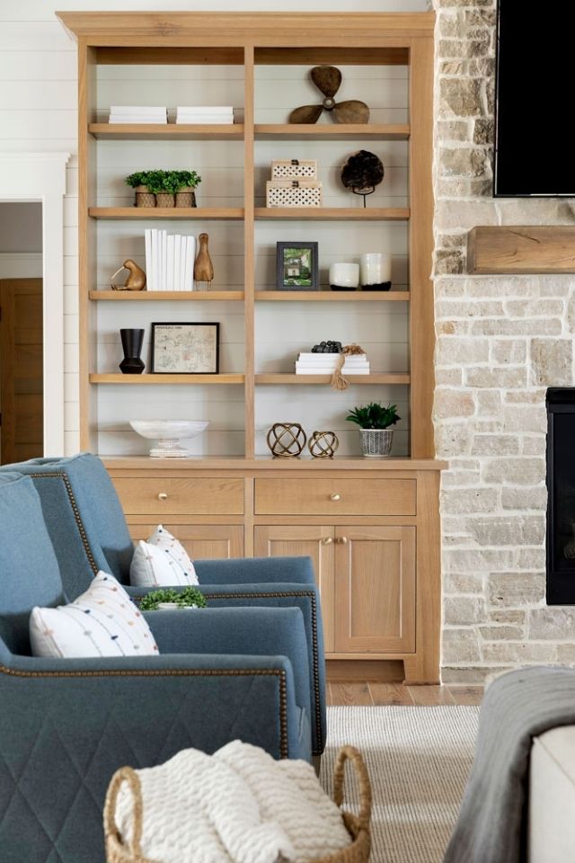 Wooden built-ins next to stone fireplace in lake home with decor